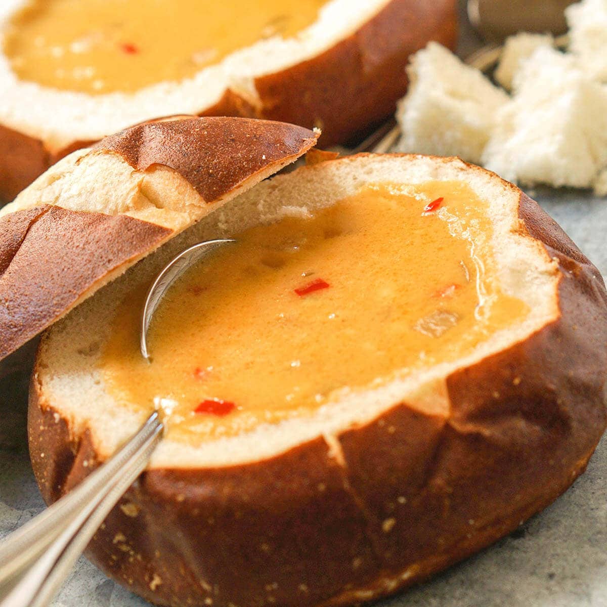 Cheese Soup in bread bowls with spoon.