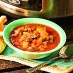 Vegetable beef stew in green bowl with spoon.