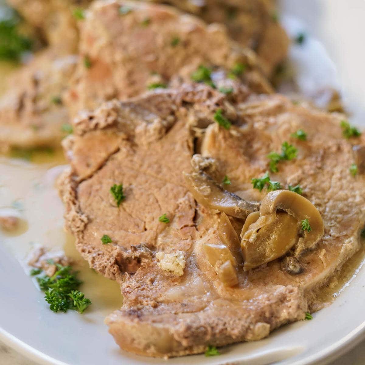Cooked chops on white platter topped with mushroom gravy.