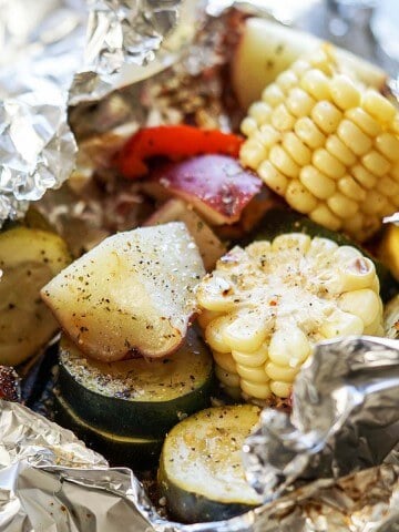 Grilled vegetables in foil packet - corn, potatoes, zucchini and onions.