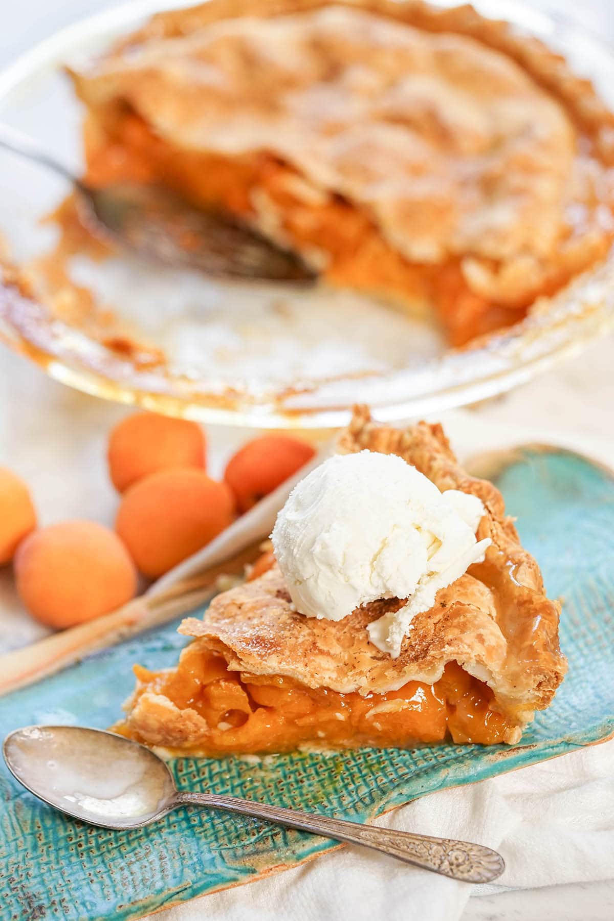Sliced Pie on plate with spoon. Pie is topped with a scoop of ice cream. 