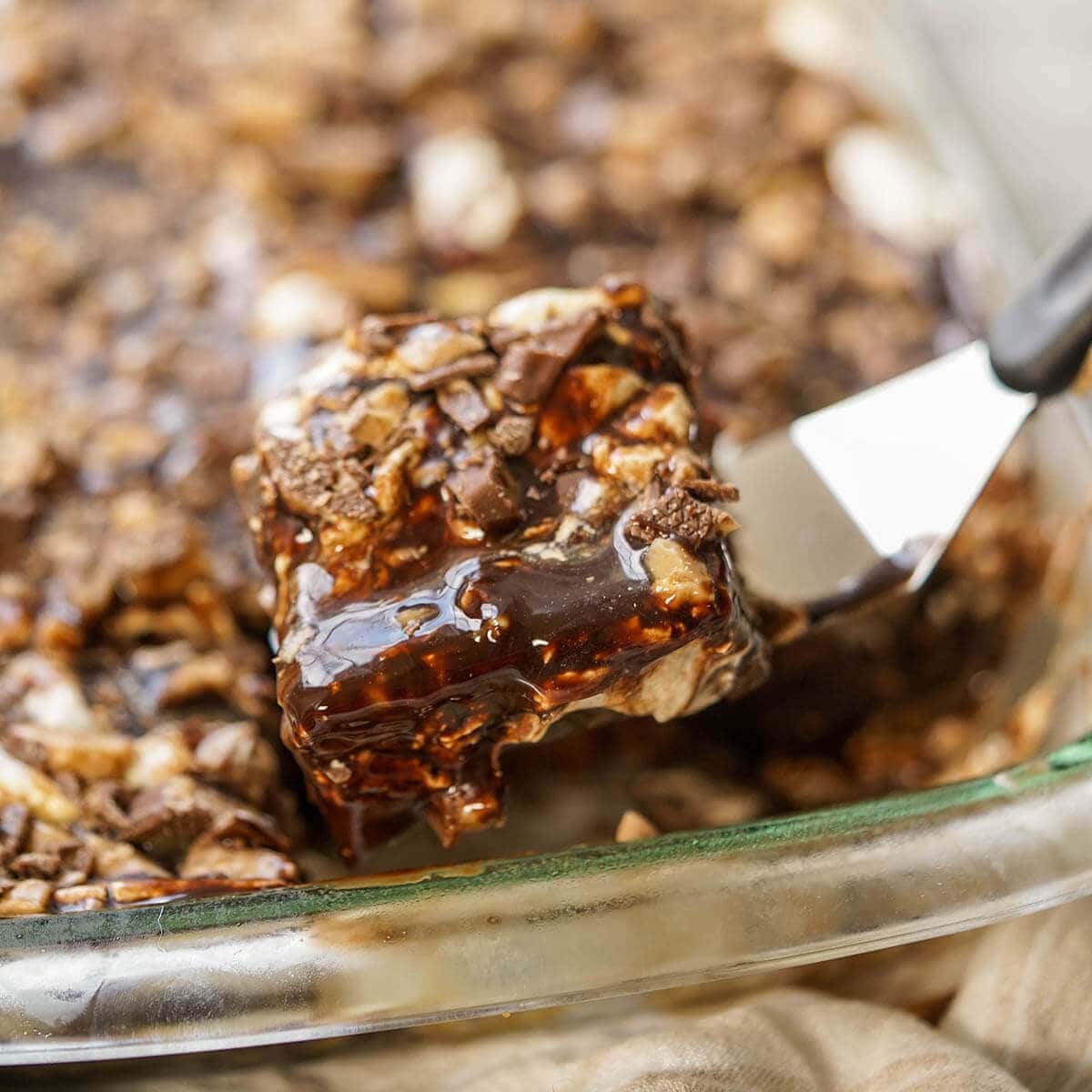 Heath Bar Cake in a glass pan being served with a spatula