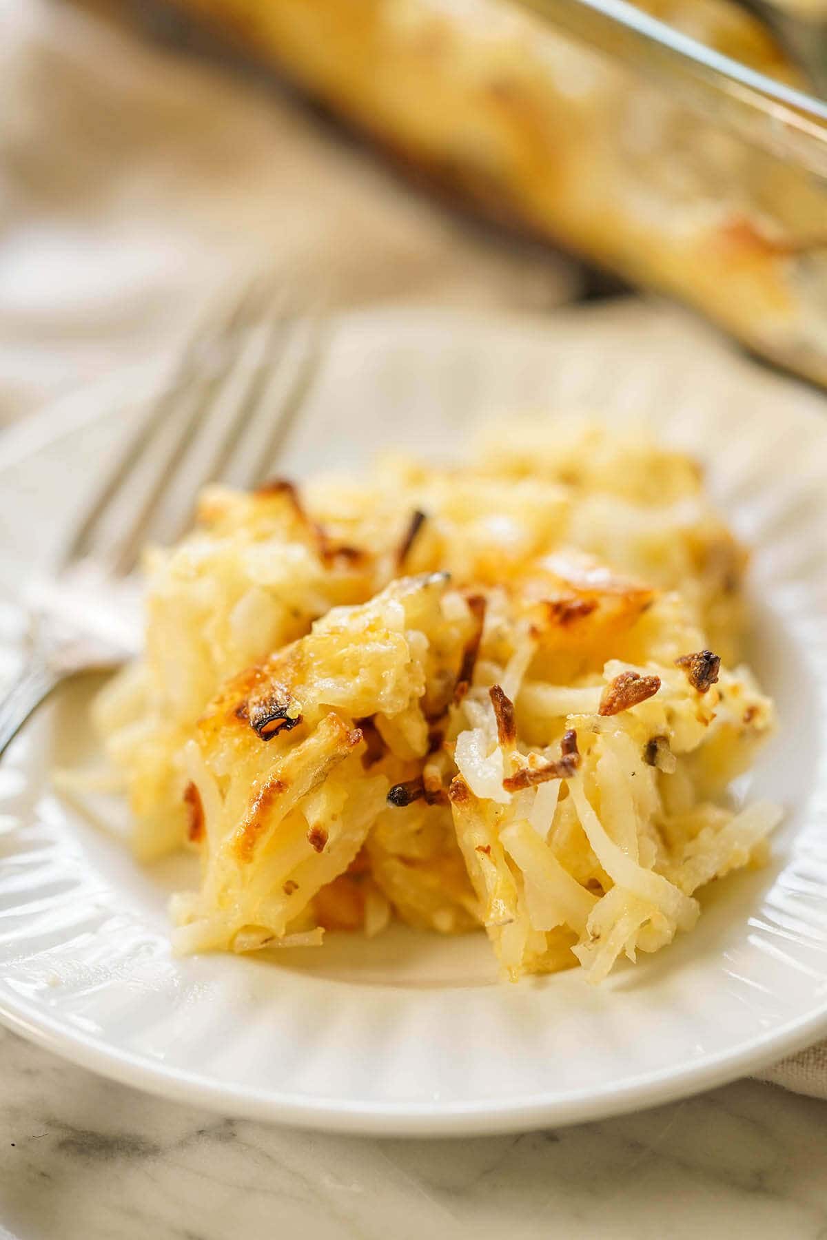 White plate filled with a serving of cheesy potato casserole