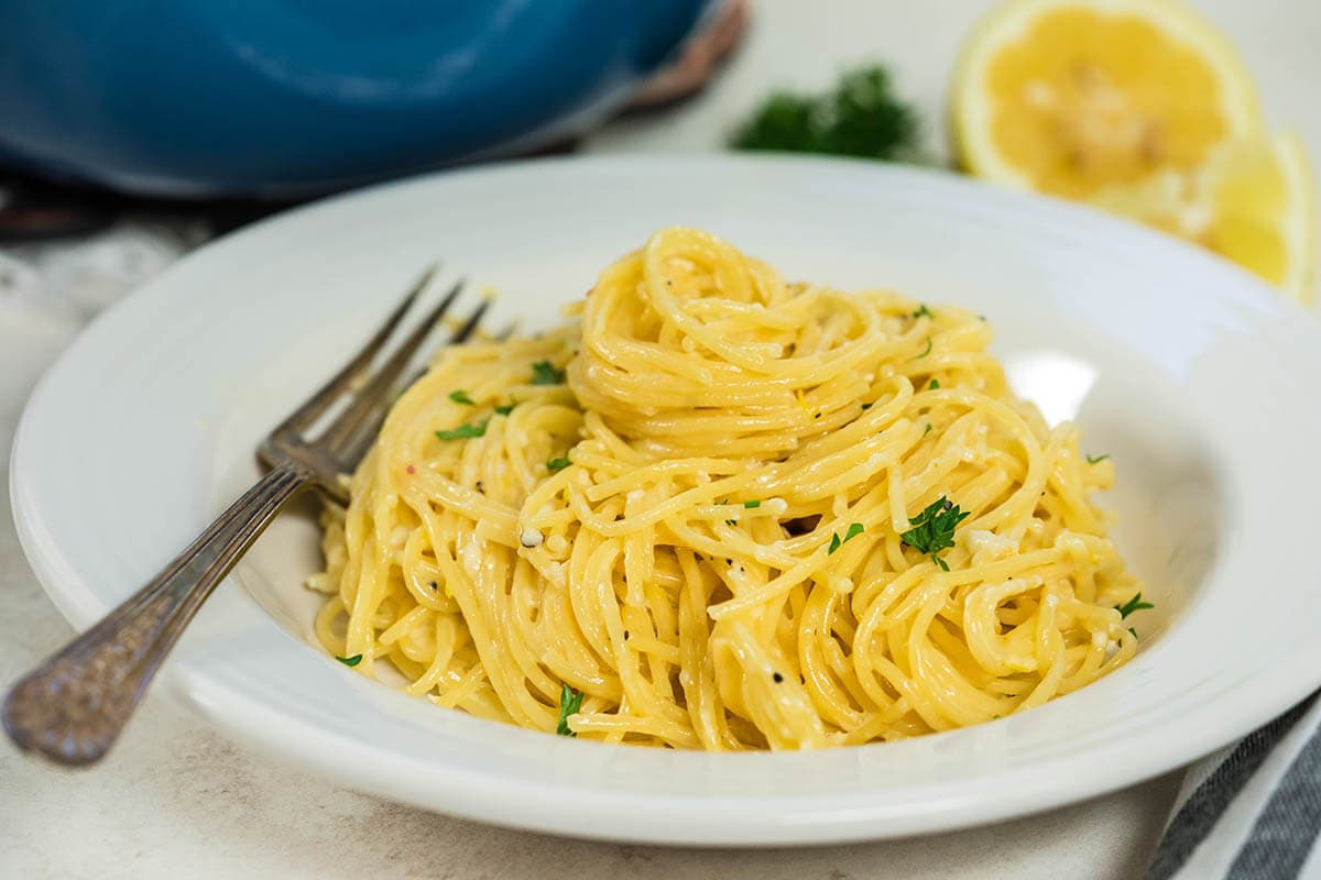 A bowl of pasta topped parsley.