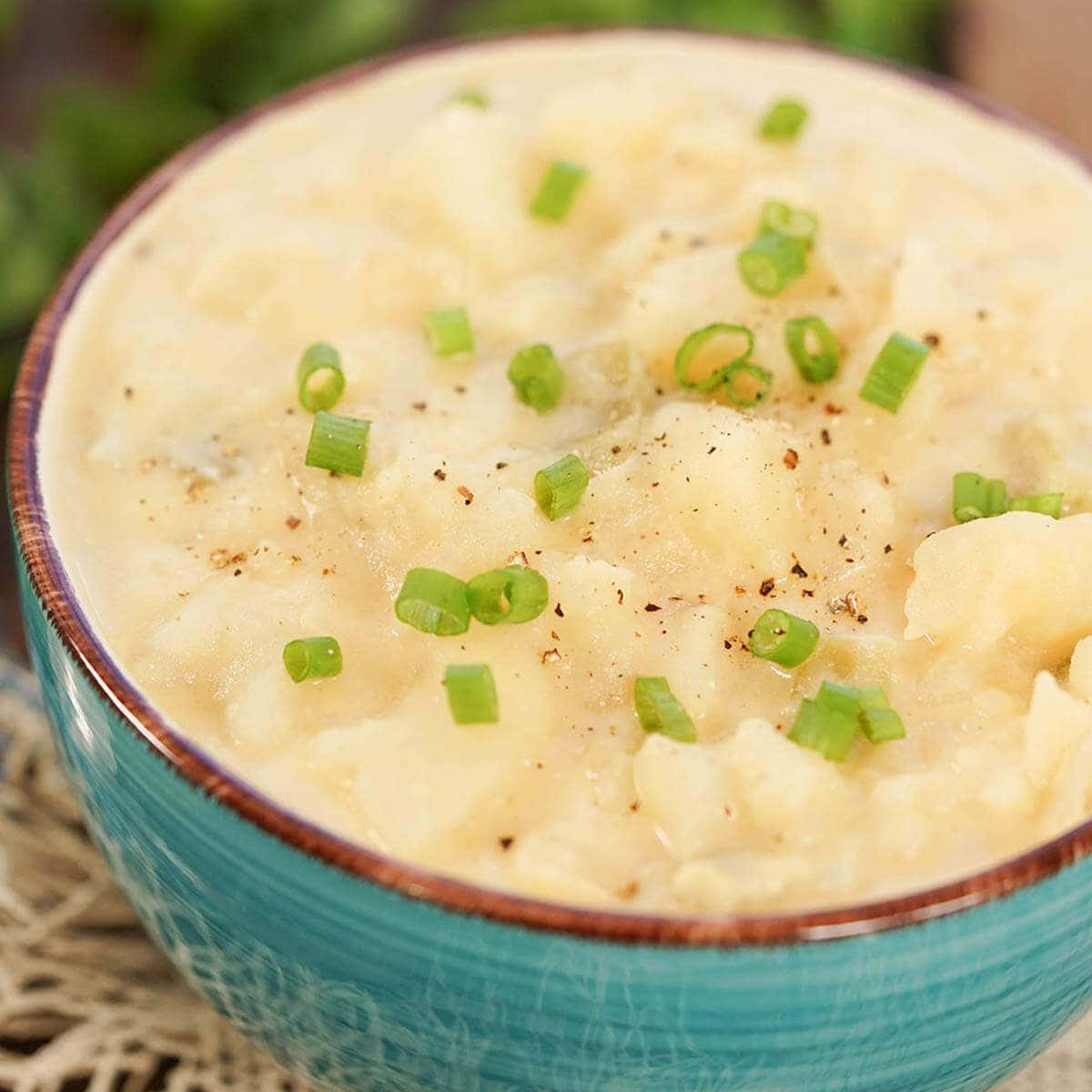 A hearty bowl of potato soup garnished with sliced green onions.