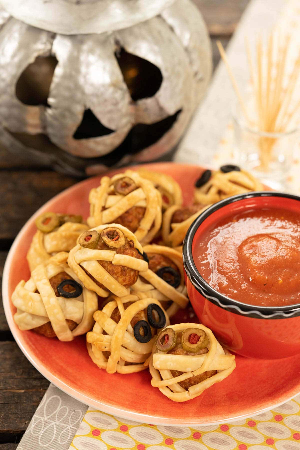 Mummy Meatball appetizers on platter with marinara sauce.