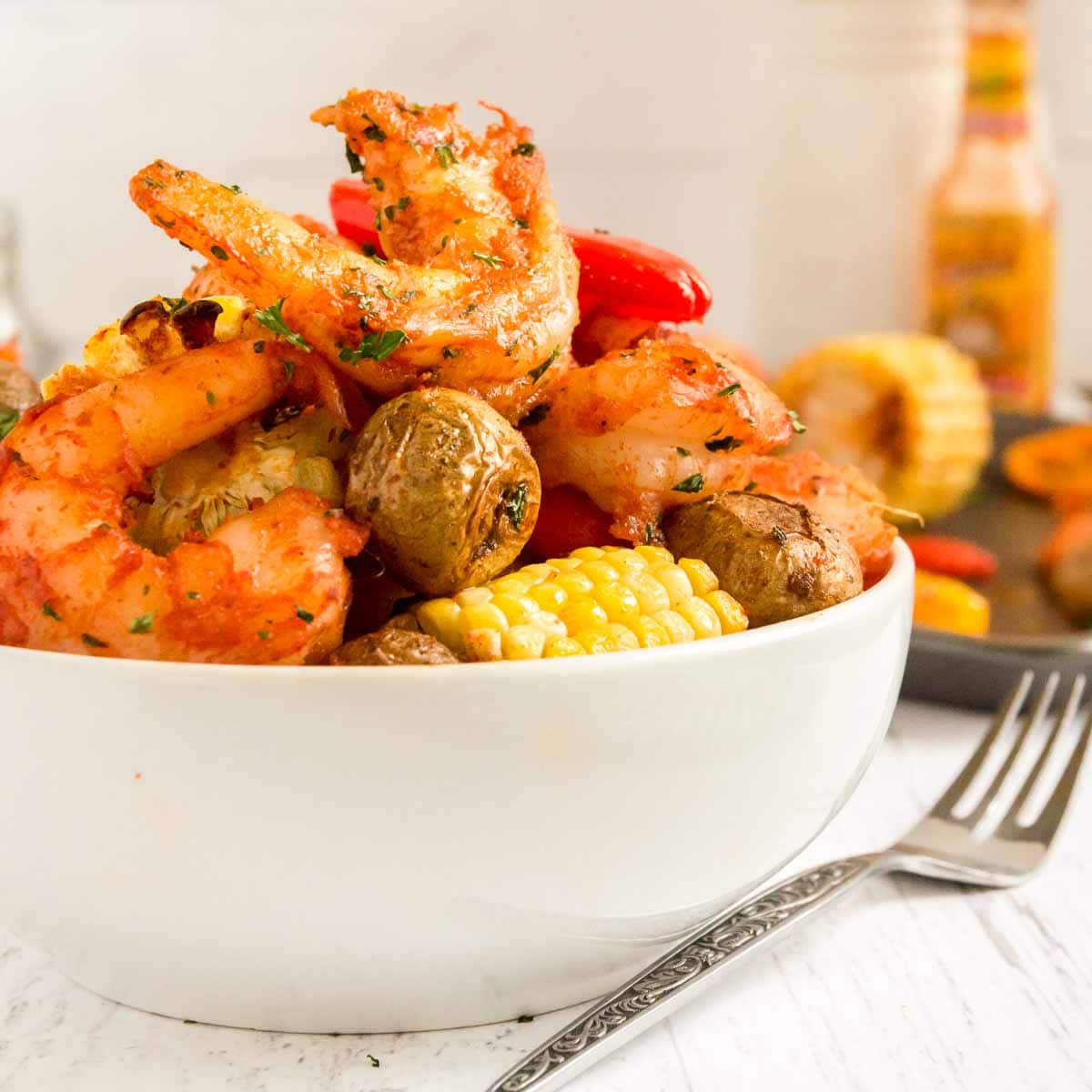 Cajun shrimp with potatoes and carrots served in a white bowl.