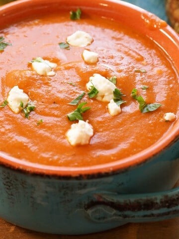 Homemade Tomato Bisque soup garnished with chunks of goat cheese and ribbons of basil.