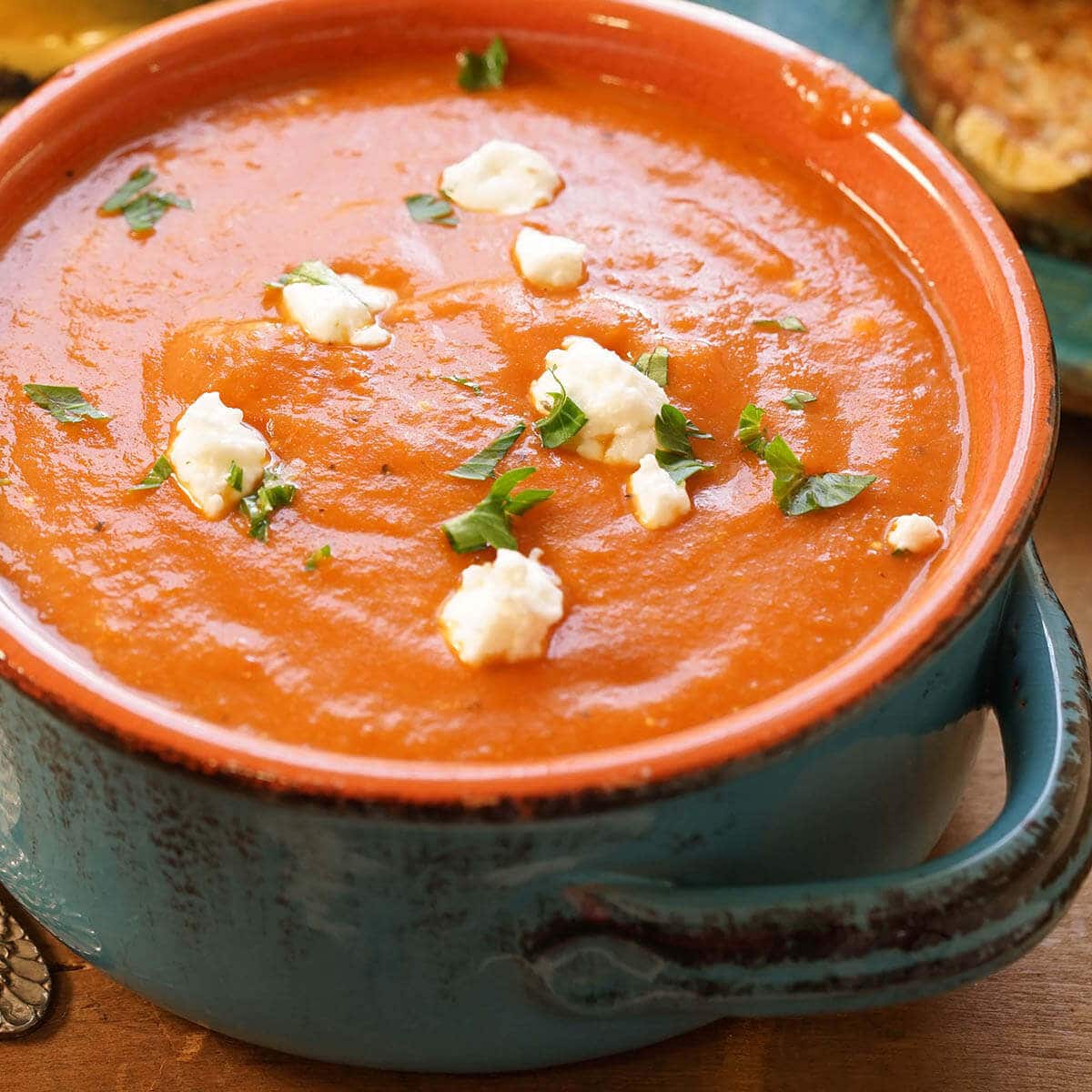 Homemade Tomato Bisque soup garnished with chunks of goat cheese and ribbons of basil.