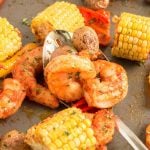 Cajun Sheet Pan Shrimp with corn, peppers and shrimp with spoon.