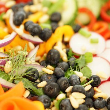 A garden salad filled with fresh veggies and blueberries.