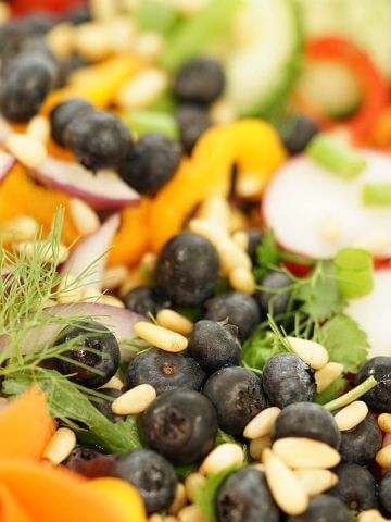A garden salad filled with fresh veggies and blueberries.