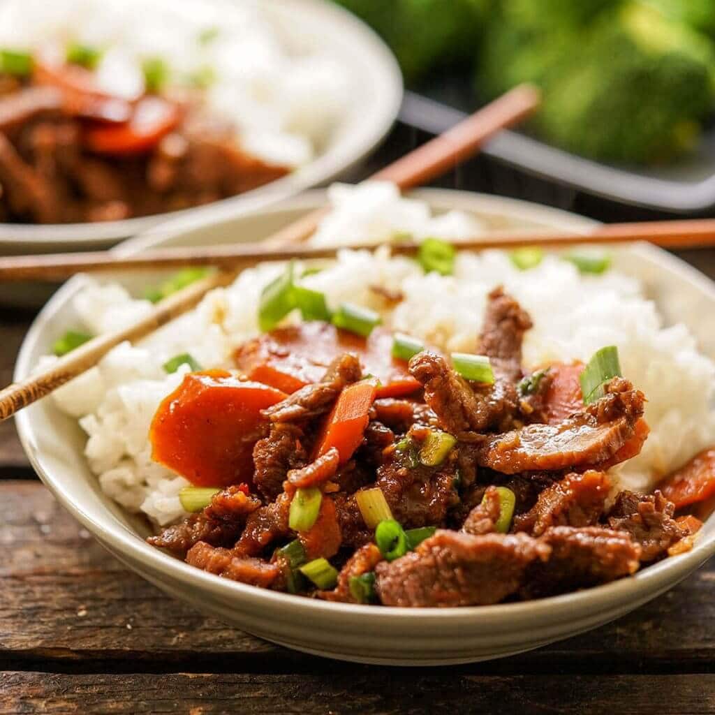 Mongolian Beef served over rice with chopsticks.