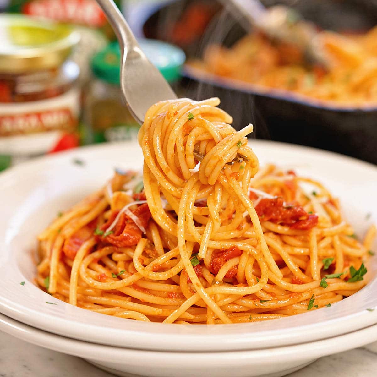 Bowl of Pasta Puttanesca and pasta twirling on fork.