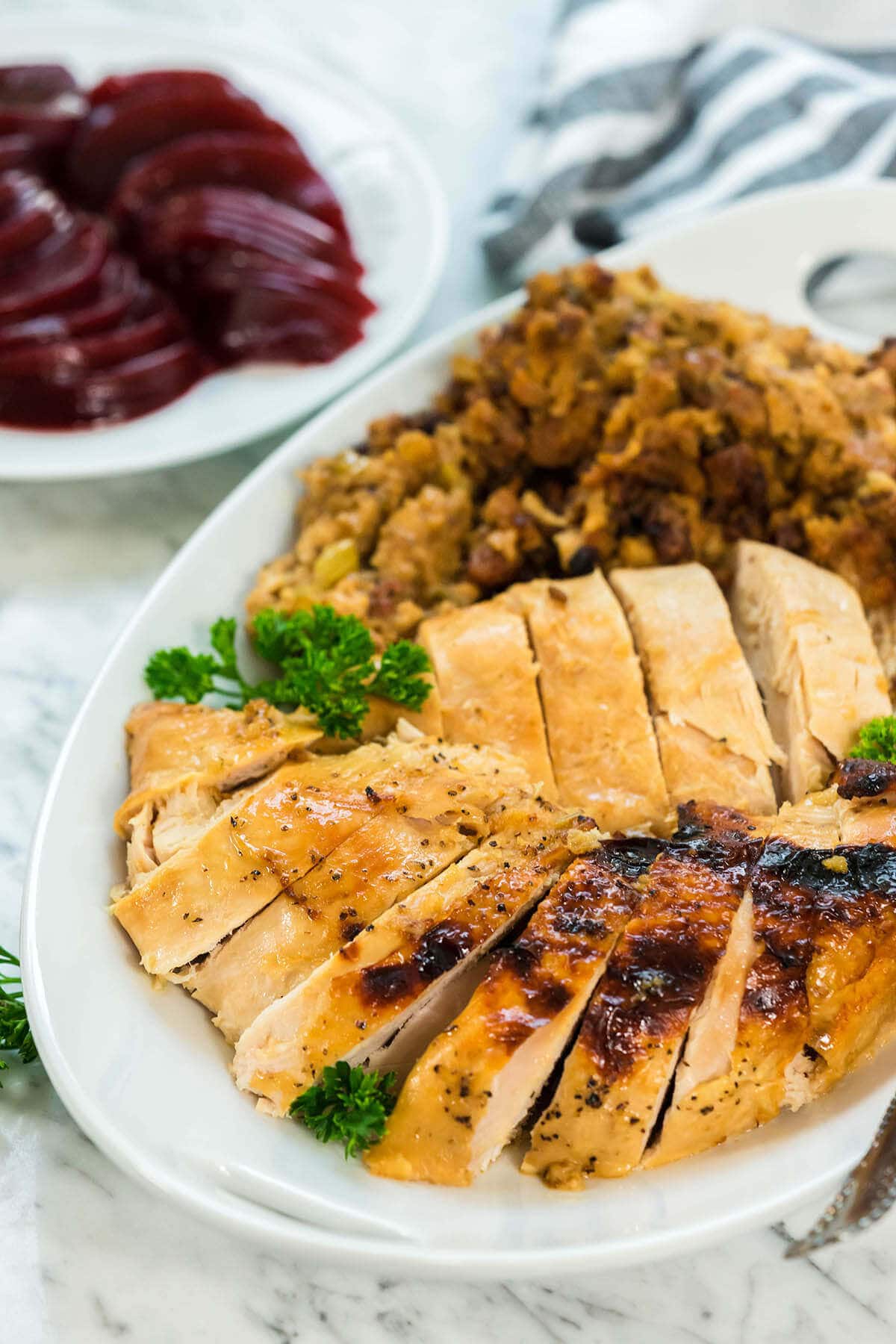 A platter filled with sliced turkey breast and stuffing. 