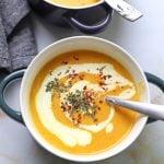 A bowl of carrot soup with a spoon in it.