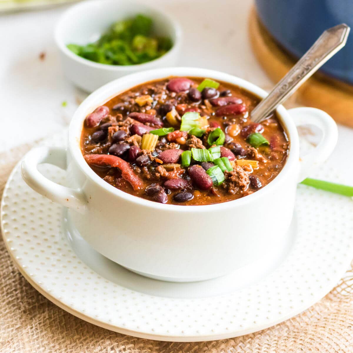 Closeup of chili in a white bowl with a spoon, ready to be enjoyed.