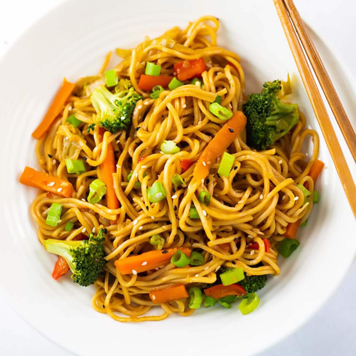 Vegetable lo mein served with chopsticks.