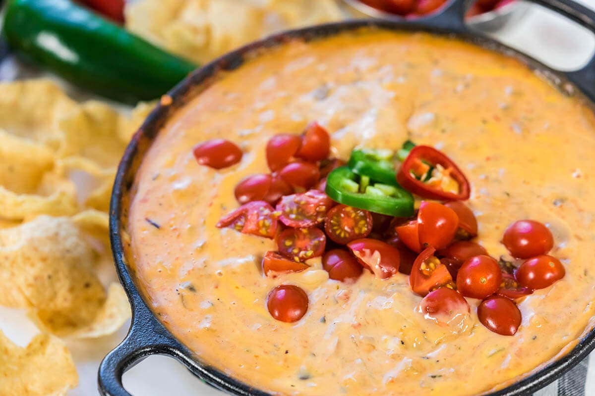 Velveeta Cheese Dip in cast iron skillet topped with tomatoes and surround by chips.