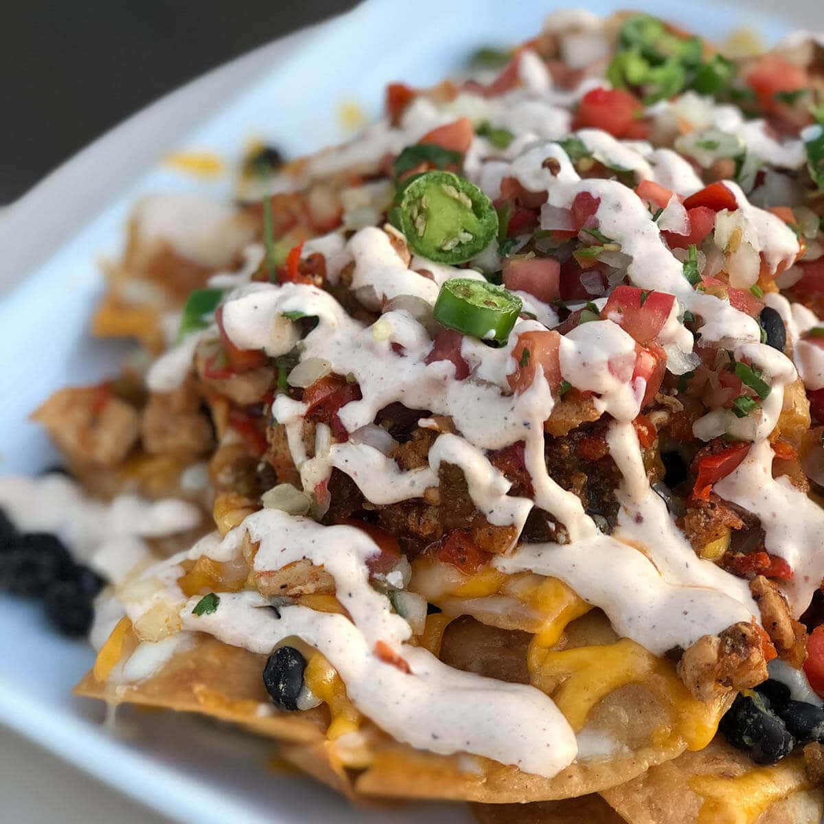 A platter of chili nachos topped with sour cream.