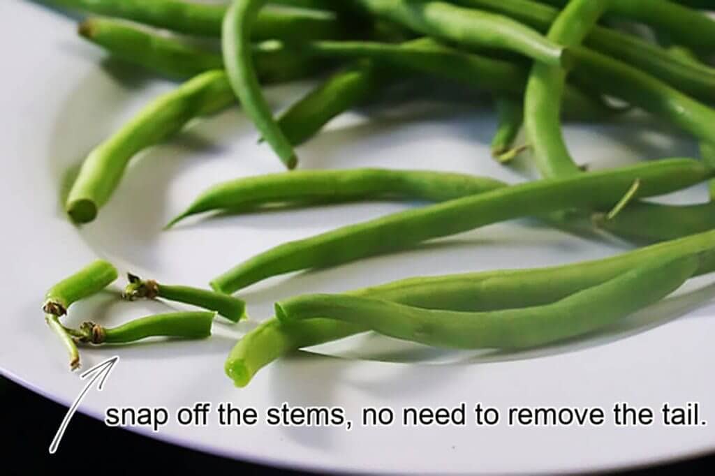 How to prepare the vegetable with an example. Green beans are on a plate, with stems snapped off. 