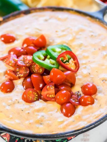 Mexican Velveeta Cheese Dip in cast iron skillet topped with tomatoes.
