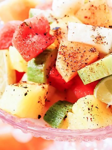 Mexican Fruit Salad topped with Tajin in pink bowl.