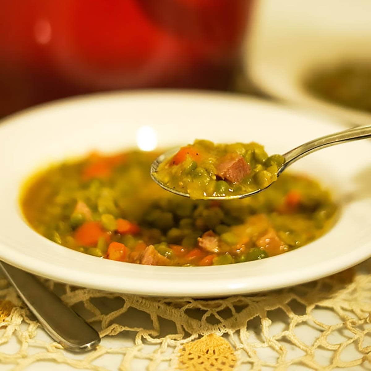 Split pea soup in white bowl with spoon.