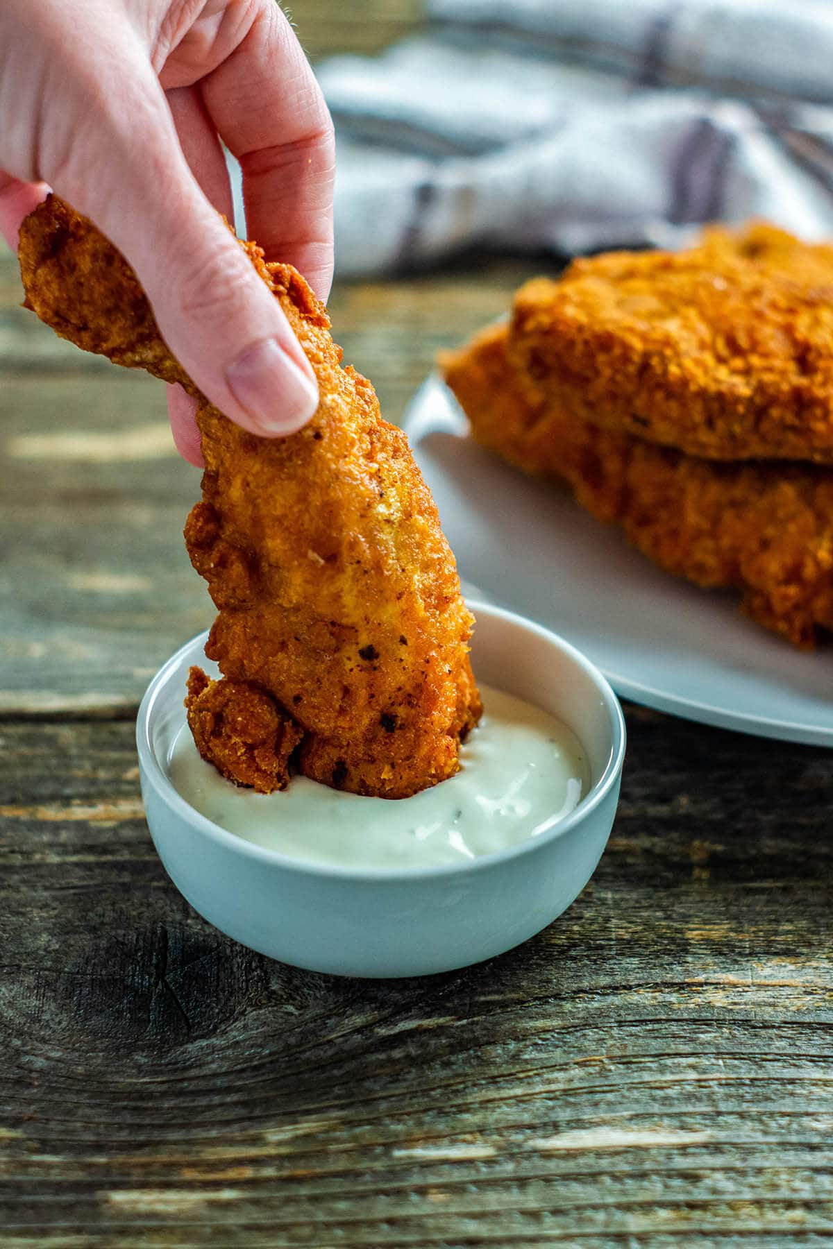 Fried chicken tender dipped into ranch sauce.