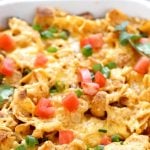Casserole topped with chips, cheese, tomatoes, thinly sliced white onions and cilantro. With Pinterest overlay.