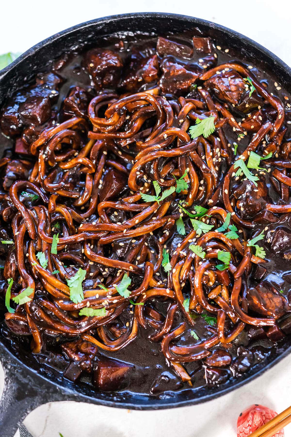 Korean Black Bean Noodles in a skillet topped with cilantro and sesame seeds.