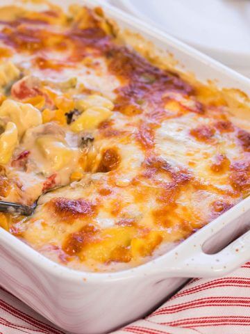Baked Tortellini in white casserole dish with spoon.