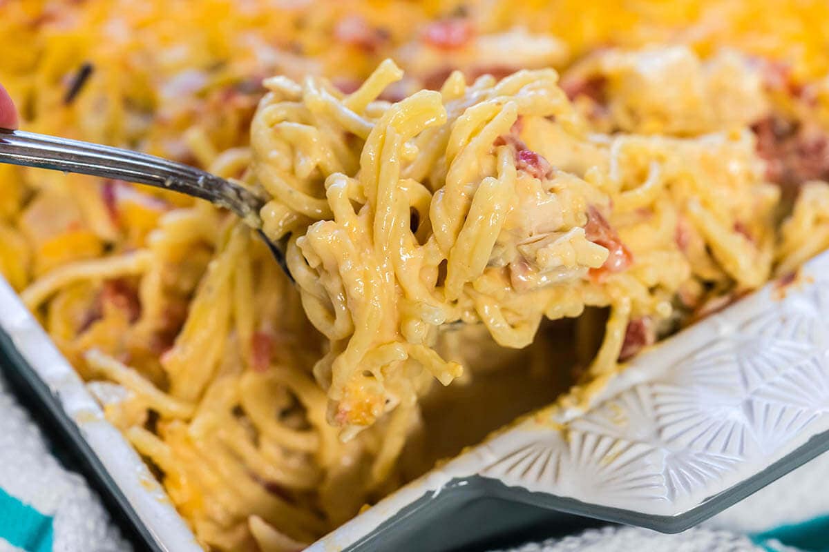 Casserole dish filled with creamy pasta dished up with spoon.