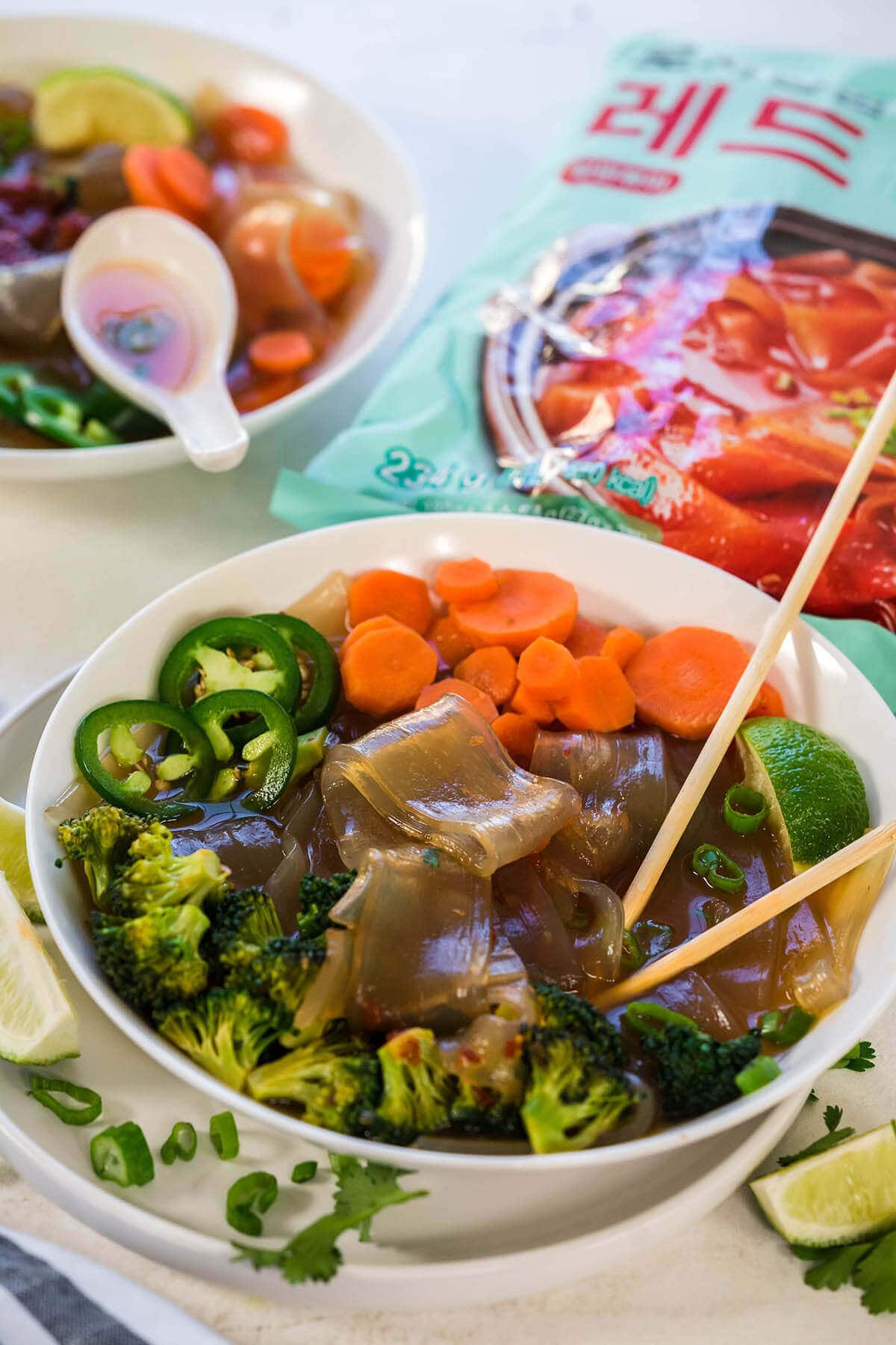 Two bowls of Glass Noodle Soup with chopsticks and spoon.