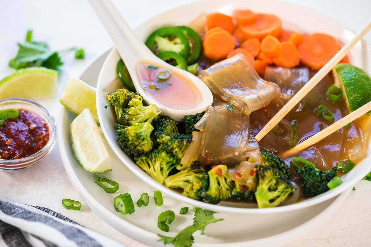 Korean Glass Noodle Soup in bowl with chopsticks and spoon.