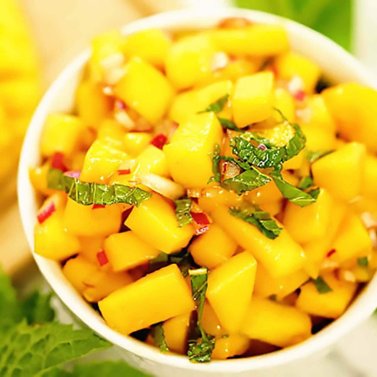 Spicy Mango Salsa in white bowl topped with mint.