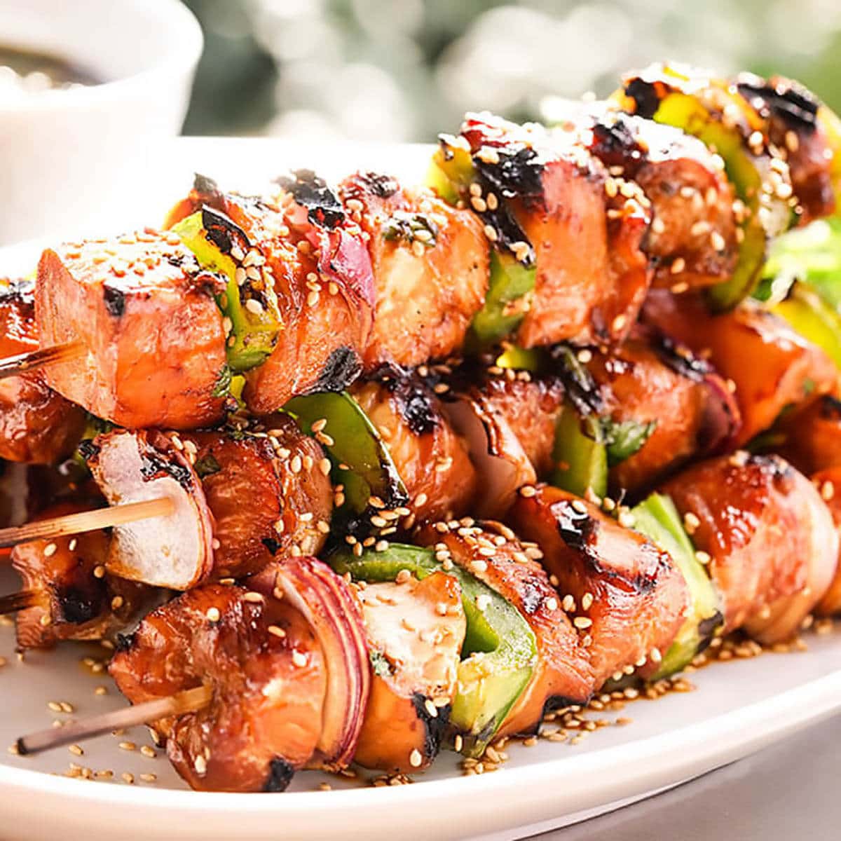 A stack of grilled teriyaki chicken kabobs on platter.