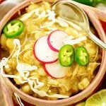 Chicken Posole garnished with jalapeños, with serving spoon.