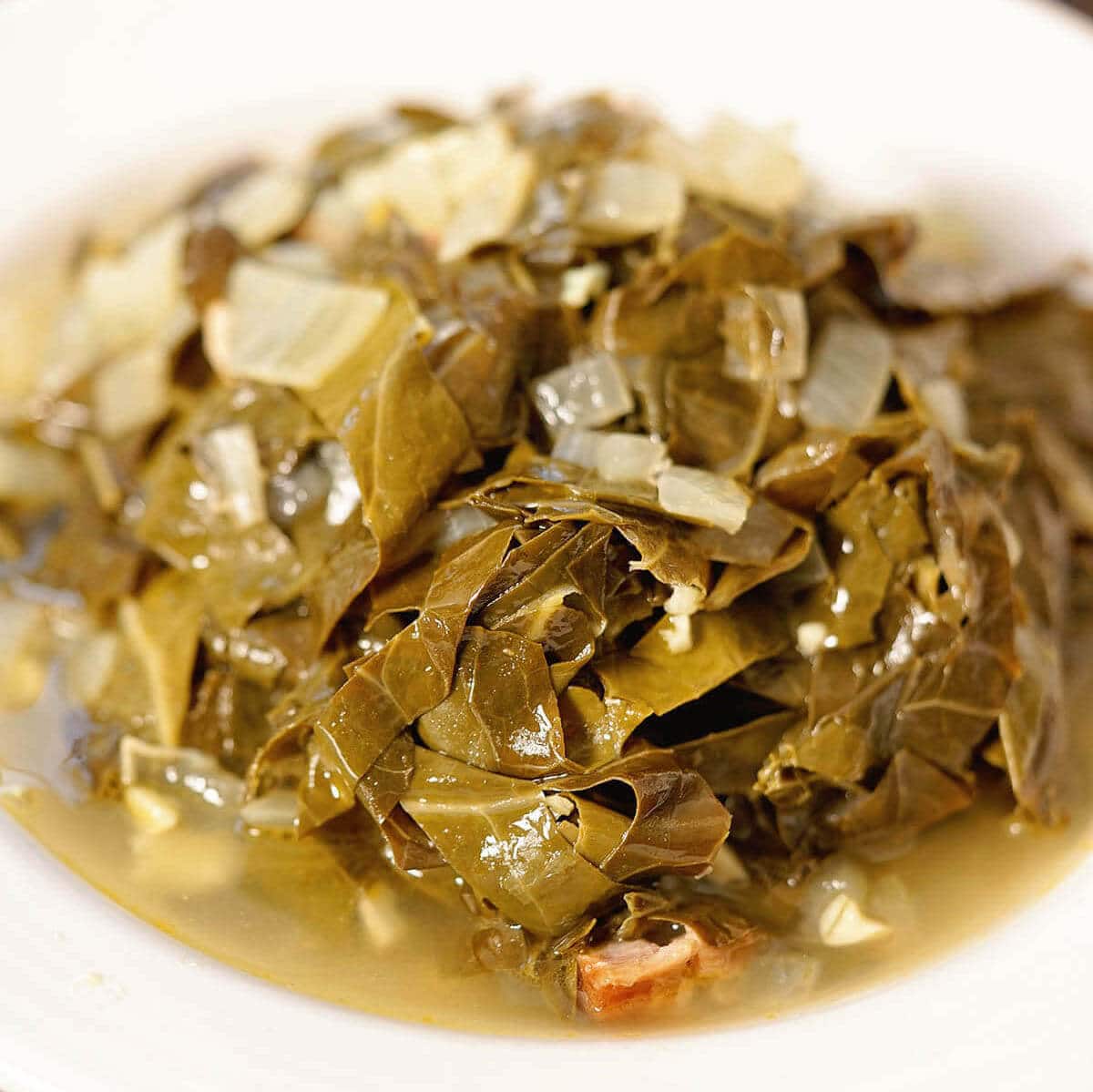 Southern style collard greens piled in a white bowl. 
