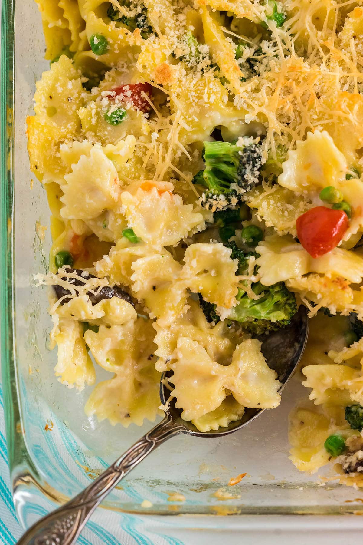 Casserole Dish filled with Creamy Pasta Primavera with serving spoon.