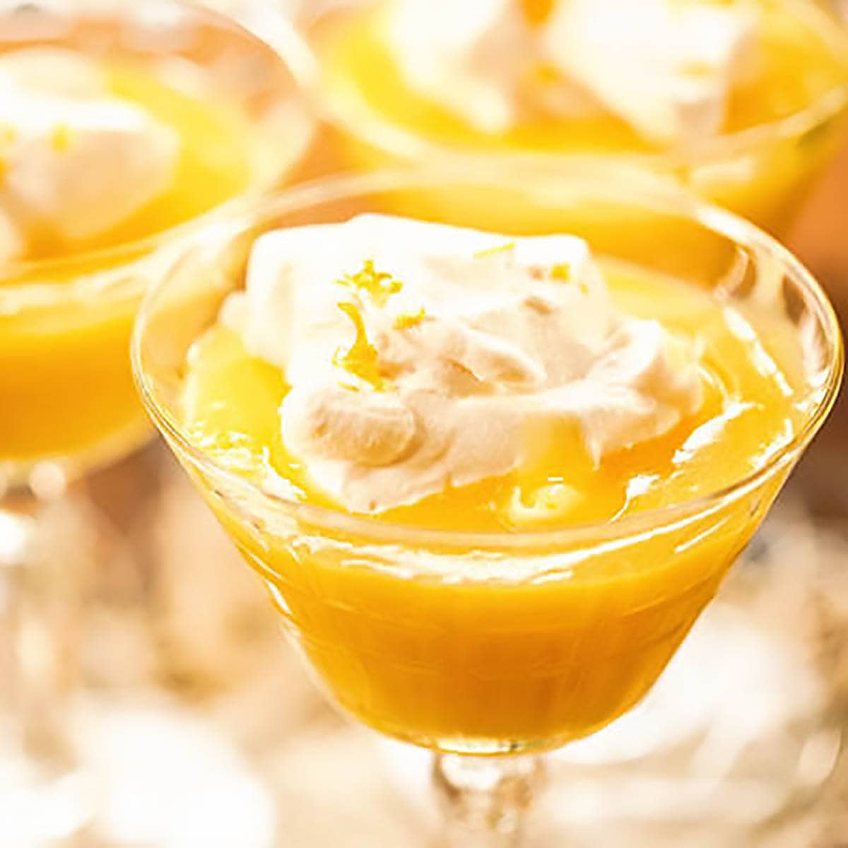Lemon pudding in glass cup topped with whipped cream.