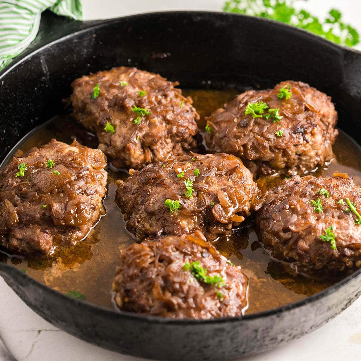 Cast Iron Skillet filled with Salisbury steak with onion gravy.