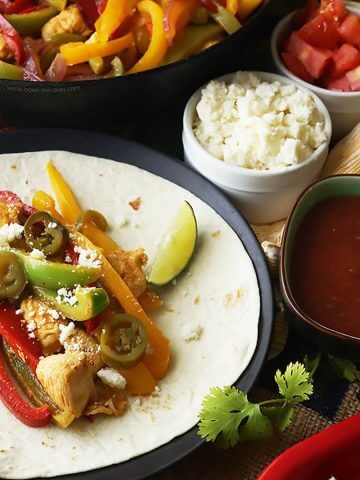 Fajitas on flour tortilla with cheese, tomatoes and sauce for seasoning.