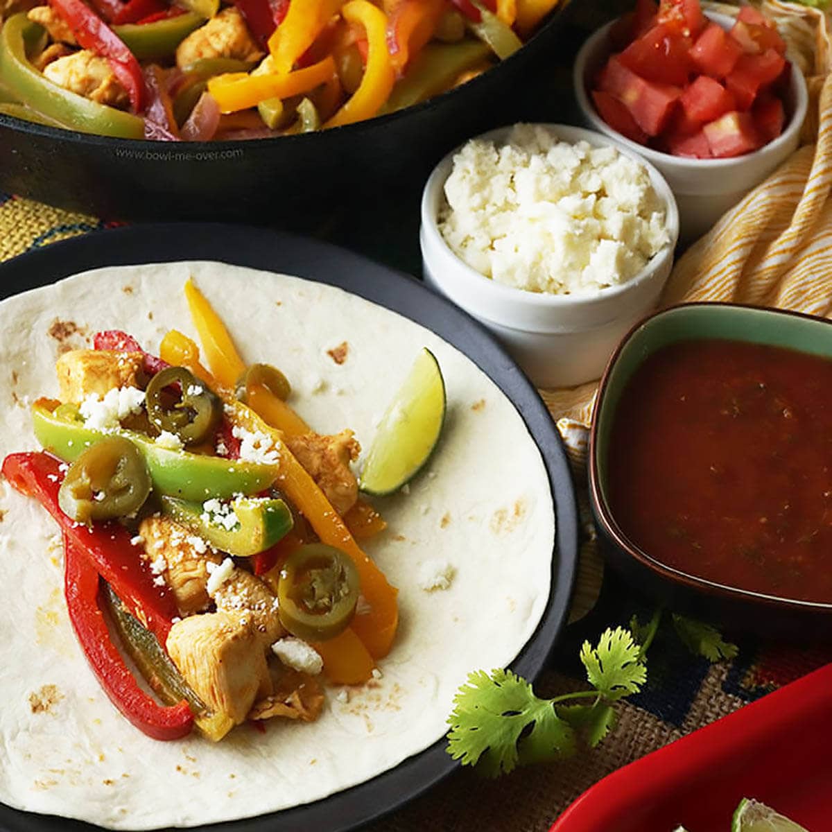 Fajitas on flour tortilla with cheese, tomatoes and sauce for seasoning. 