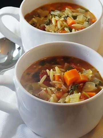 Vegetable Orzo Soup in white bowls with serving spoons.