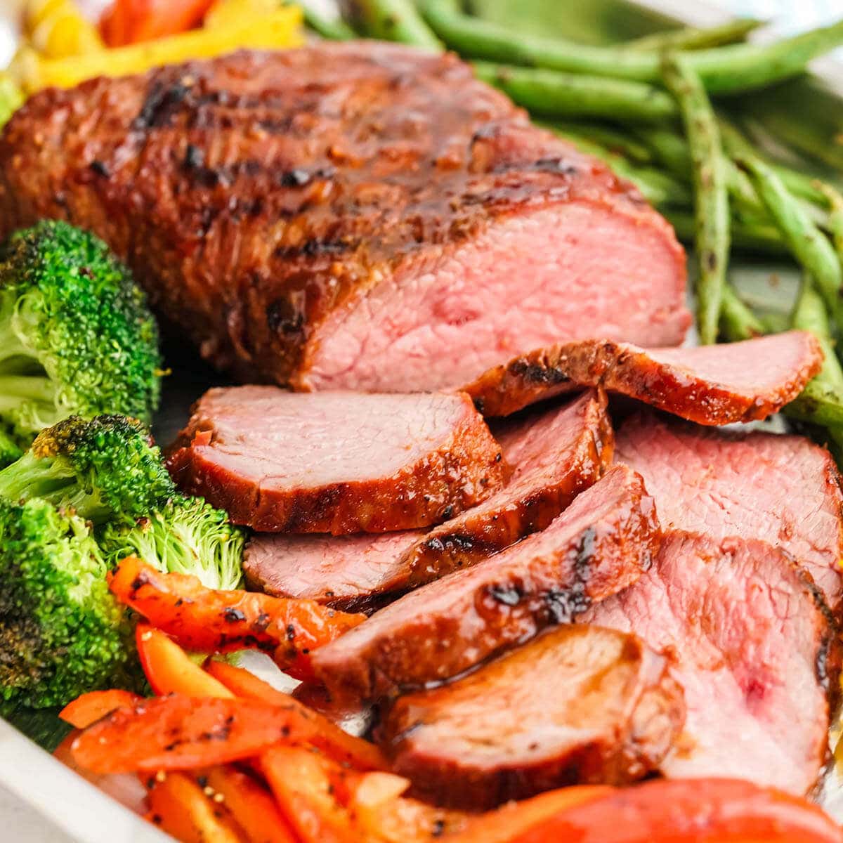 BBQ Tri Tip on platter surrounded by grilled veggies.