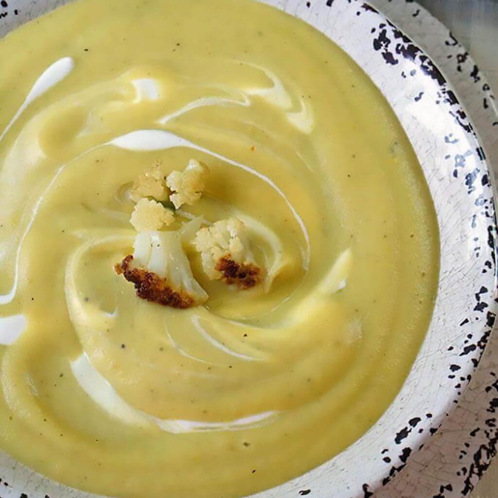 Creamy Cauliflower Soup in bowl topped with pieces of roasted cauliflower.