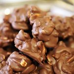 A silver plate filled with chocolate covered cashew nut clusters.