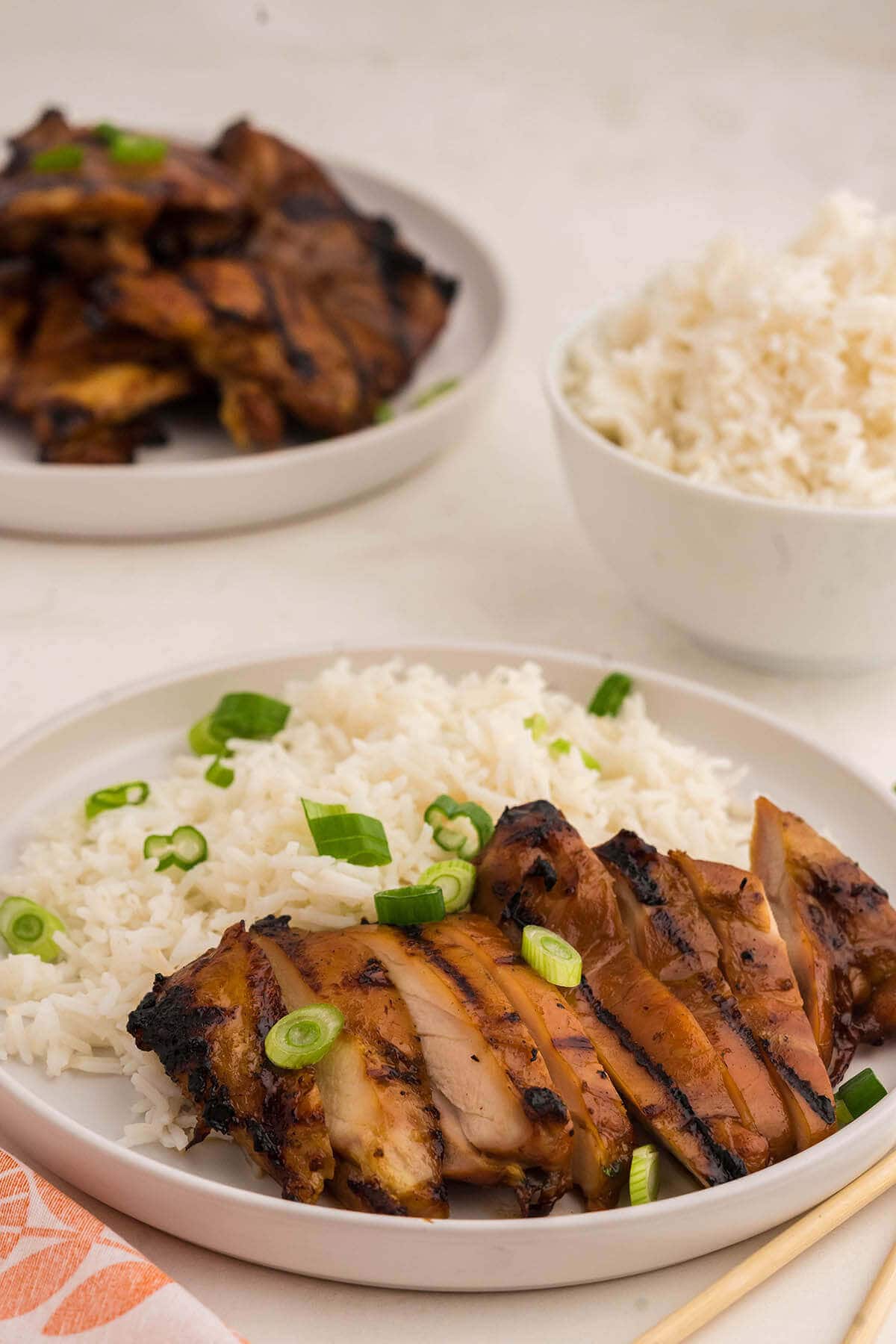 Sliced Teriyaki Chicken thighs on white plate with rice.