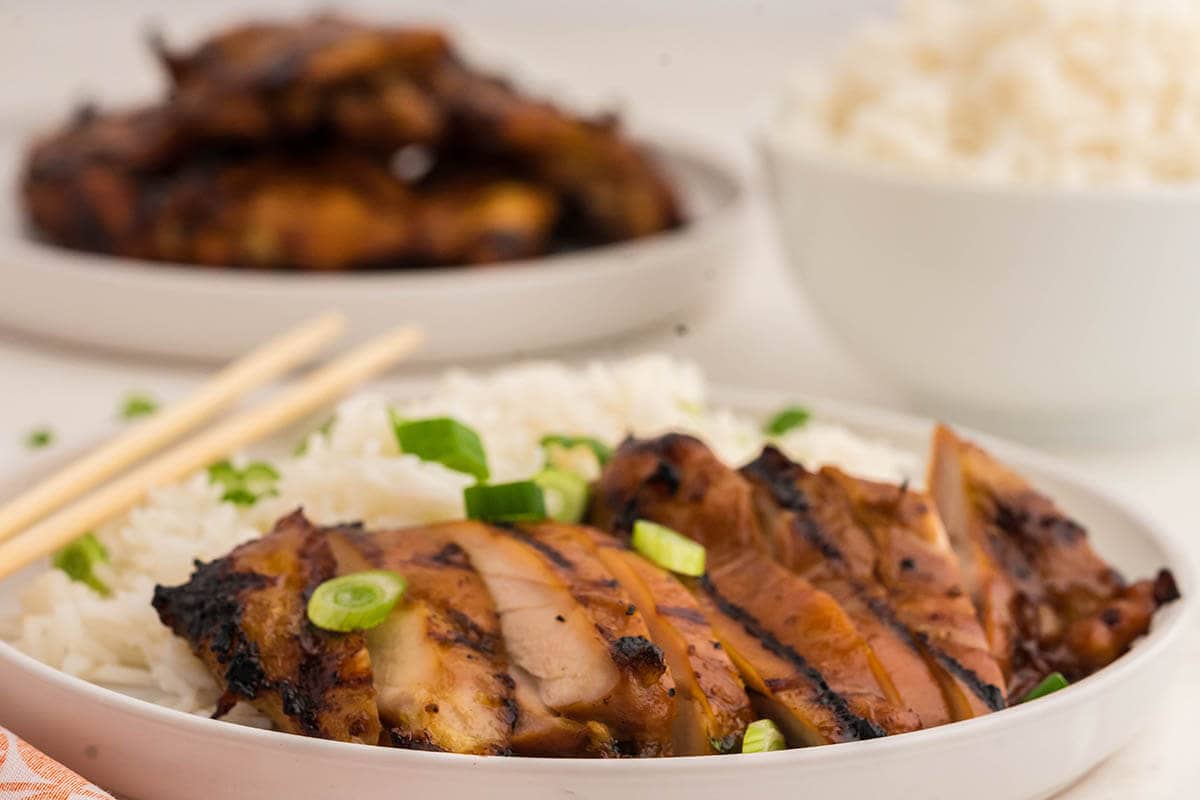 Sliced Teriyaki Chicken served with rice and garnished with chopped green onions.